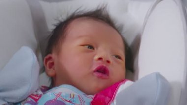 Bebek yatağında yatıp kameraya gülümseyen mutlu bir bebek masum gözleri rahat ve rahat bir Asyalı bebek. Yeni doğan bebek fotoğrafçılığı konsepti.