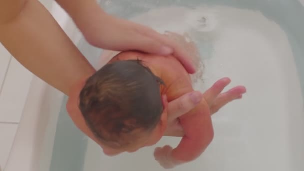 母亲在温暖的水中给她的儿子洗澡 7天可爱的新生儿在浴缸里微笑放松舒适 — 图库视频影像