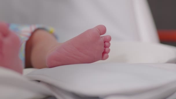 赤ちゃんのベッドの上に横たわる新生児の裸足で閉じるリラックスして快適な 乳児の小さな足は自宅でベッドの上に移動 新生児の写真のコンセプト — ストック動画