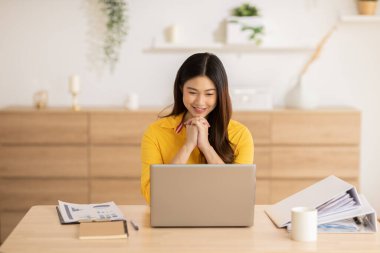 Girişimci güzel iş kadını Asyalı genç kadın evde dizüstü bilgisayarla İnternet üzerinden sarı tişört giyiyor. Home.mall Business Startup konseptinde online satış pazarlaması yapan serbest çalışan bir kadın.