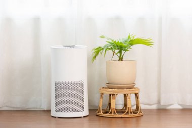 Evdeki tozu, PM2.5 HEPA 'yı ve virüsü, temiz hava ve sağlıklı yaşam için, hava kirliliği kavramını temizlemek ve filtrelemek için rahat beyaz oturma odasında hava temizleyicisi.