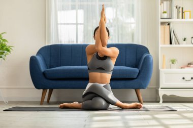 Çekici Asyalı kadının sakinliği yoga kartalı ya da Garudasana pozu evde esneme ve meditasyon için çok rahat ve rahat, sağlık sigortası konsepti
