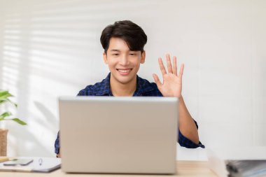 Girişimci yakışıklı iş adamı günlük mavi gömlekli iş adamı laptop ile video konferansında çalışıyor, ev ofisteki müşteri veya iş ekibiyle konuşuyor. İş Kuruluşu Konsepti