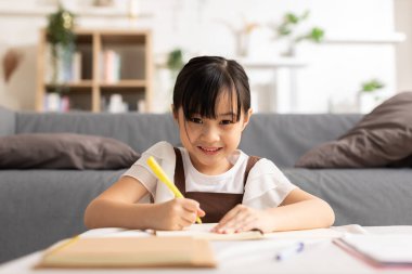 Küçük Asyalı kız çocuğunun portresi evde gülümsemeyi ve mutluluğu öğreniyor. Yeteneğini ve duygusal niteliğini geliştirmek için güzel bir kız çizimi ve el yazısı. Ev Okulu Eğitim Konsepti