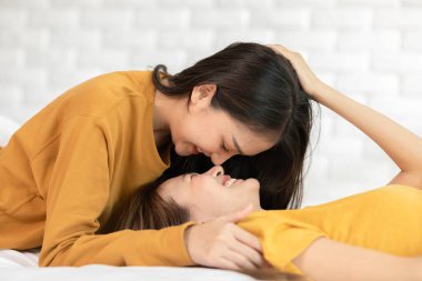 Güzel iki kadın LGBT lezbiyen kucaklaşıyorlar ve yatakta aşk ve romantizmle birlikte bakıyorlar. Pozitif ruh hali ve LGBTQ lezbiyen beyaz yatakta uzanıyor rahatla ve rahatla. LGBTQ Gurur Yaşam Tarzı Ayı