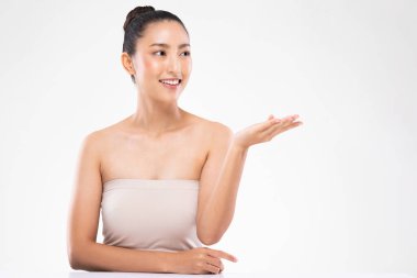 Güzel, alımlı Asyalı genç kadın gülümsüyor beyaz dişleri açık, kozmetik ürünleri için avucu açık sağlıklı ciltli, beyaz arka planda izole edilmiş güzellik kozmetik konsepti.