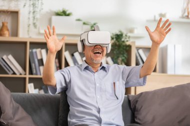 VR ya da Sanal Gerçeklik gözlüğü kullanan mutlu yaşlılar nesneleri işaret ediyor ya da metaevrendeki arkadaşlarıyla topluluk içinde konuşuyor. Heyecanlı ve şaşırmış kıdemli Asyalı bir adam VR kullanarak gözlüklerle eğleniyor.