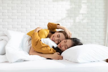 LGBT lezbiyen uyandı ve yatakta aşk ve romantizm içinde birlikte bakıyorlar. Pozitif ruh hali ve LGBTQ lezbiyen beyaz yatakta uzanıyor rahatla ve rahatla. LGBTQ Yaşam Tarzı Confestyle