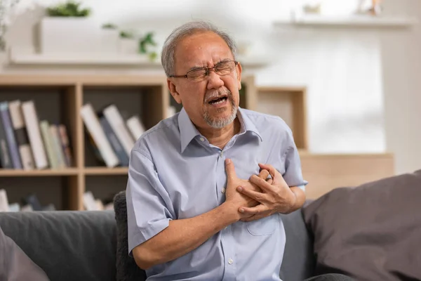 Elderly Asian Male Heart Attack Sitting Couch Living Room Senior — стоковое фото