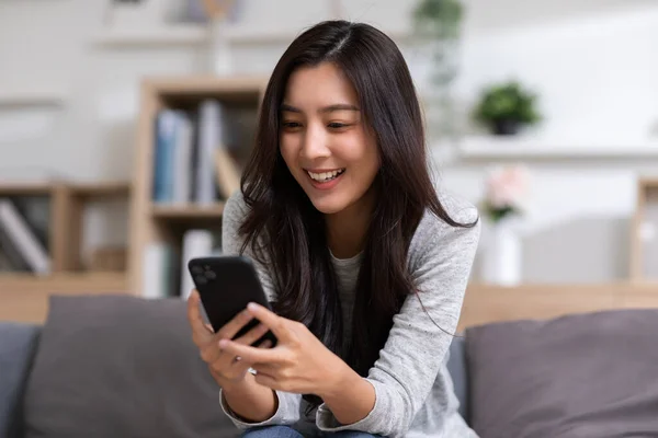 幸福起業家美しいビジネスアジアの若い女性は自宅でソーシャルメディアやラップトップでオンラインショッピングのためのカジュアルな使用の携帯電話を身に着けています — ストック写真