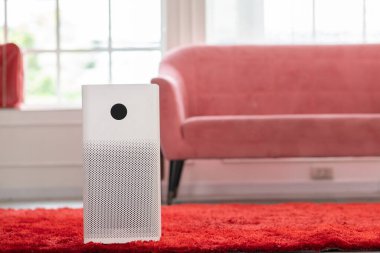 Evdeki tozu, PM2.5 HEPA 'yı ve virüsü, temiz hava ve sağlıklı yaşam için, hava kirliliği kavramını temizlemek ve filtrelemek için rahat beyaz oturma odasında hava temizleyicisi.