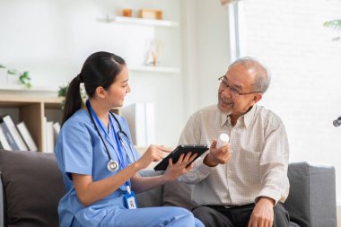 Ofiste çalışan ve hastalara danışmanlık yapan bir doktor, sağlık hizmetleri semptomlarını açıklıyor ve yaşlı bir adama yardım ediyor, ilaç veriyor. Teşhis ve semptomların yazılması, yaşlı bakımı, sağlık konsepti.