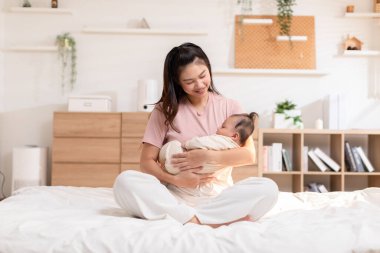 Sevimli yeni doğmuş bebek gülümse ve anne kollarında rahatla. Sağlıklı Asyalı yeni doğmuş bebek mutlulukla gülüyor. Anne kucağında bebek bebeği kavramı.