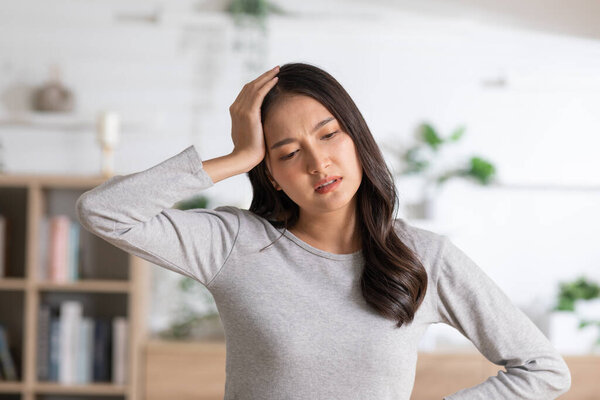An Asian woman has got and headache and frown face. She seems stressed out and try to squeezing her nose to release her stressful. Headache and brain issues can be caused of stroke.