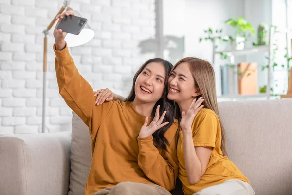 Genç Asyalı kadın çift birlikte fotoğraf çekiyor. LGBTQ 'lu lezbiyen çift tişört giyiyor ve birlikte kıkırdıyor. Normal çiftler ve LGBT kavramsal olarak birlikte vakit geçiriyorlar..