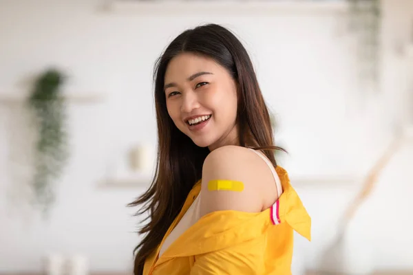幸せなアジアの女性は黄色の包帯で明るく親指の抗ウイルスワクチンを受けました Covid 19ワクチン接種後の将来の安全生活を楽しみ自信を持つ若い女性 ワクチン接種コンセプト — ストック写真