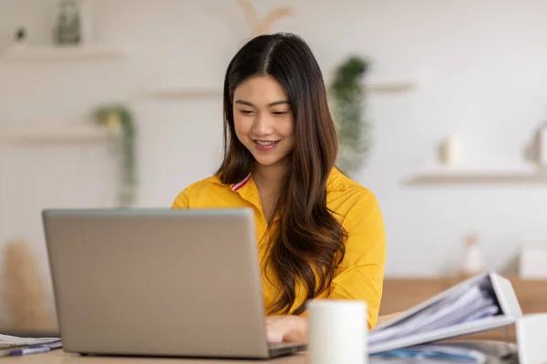 起業家美しいビジネスアジアの若い女性は自宅でラップトップと黄色のシャツの仕事をオンラインで着用します — ストック写真