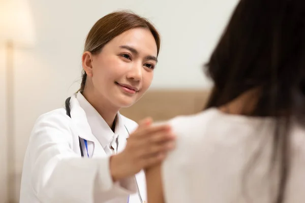 Asian female doctor giving hope and encourage to stressed woman patient at hospital. Smiling doctor woman touching on patient shoulder to support take care and helping . Supported and Encouraged