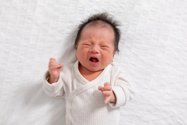 Crying and angry Newborn baby boy lying on white bed at home.Infant baby screaming very hungry or stomach pain. sick asian baby crying and having fever. Tired baby crying concept