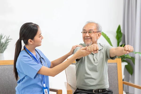 Asian female doctor advice elderly patient to physiotherapist to exercise stretching muscle at home.Smiling nurse helping senior patient workout exercise to build muscle strong.Physiotherapist Nursing