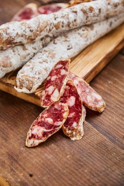 Et ürünleri, haşlanmış ve kurutulmuş sosis üretim fabrikası. Geleneksel baharatlı sosis, yemeye hazır, ahşap bir masada dilimlenmiş yatıyor. El yapımı et ürünleri kavramı.