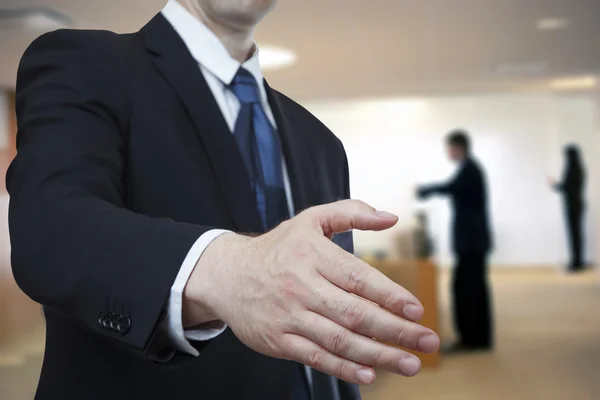 Affärsman erbjuder handslag till dig på office bakgrund — Stockfoto