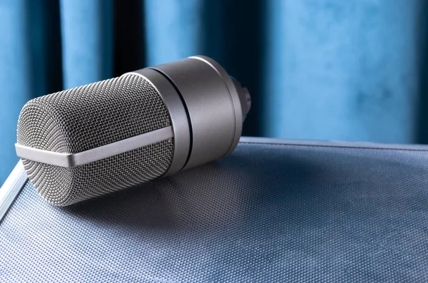 Mavi bir perdenin arkasındaki metal bir kutunun üzerindeki yoğunlaştırıcı mikrofon..