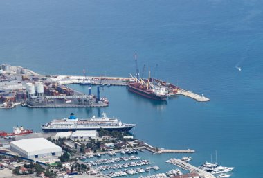 Ticari limana kuşbakışı bir bakış açısı. Bir mavna ve bir yolcu gemisi. İskelede bir sürü tekne var. Kargo Konteynerleri.