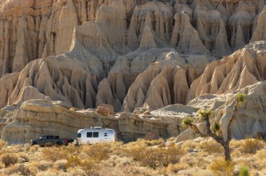 Red Rock Canyon State Park, CA, ABD - 24 Şubat 2022: aşınmış bir dağ yamacına karşı gösterilen römork Airstream ve kamyonun görüntüsü.