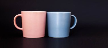 Kahve için iki fincan pembe ve gri, siyah arka planda duruyor. Mesaj için yer. Pankart. Kahve günü. Sevgililer Günü. Kapalı bardaklar. Kahveli minimalizm. Kahvaltıda. Modelleme. Kapat.