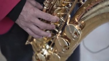 Takım elbise içinde saksafon çalan bir erkek müzisyen, canlı bir konserde çalar, parmakları bir caz grubunda yakın çekim yapar, sahnede şarkı söyler..