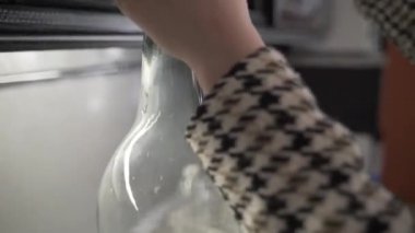 Ay ışığı büyük bir kavanoza doluyor. Ev yapımı alkol. Yakın plan bir içki özel bir şişeye doldurulur..