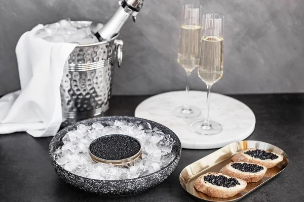 Caviar noir en boîte sur glace, sandwich au caviar sur assiette dorée, champagne en verre Images De Stock Libres De Droits