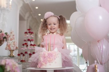 Şirin küçük kız doğum günü pastasında mumları üflüyor. 