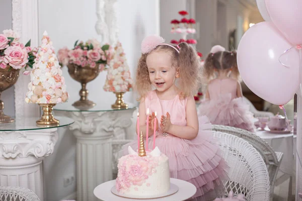 Schattig klein meisje blaast kaarsen op een verjaardag taart Stockfoto