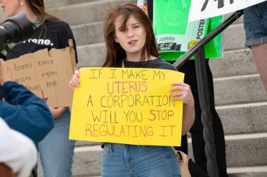 Helena, Montana - 24 Haziran 2022: Kadın uterusları düzenlemeye son vermek için tabela tutuyor, silahların daha fazla hakkı var, Montana eyaleti başkentindeki kadınlar Anayasa Mahkemesi 'nin kürtaj yasasına karşı çıkmalarını protesto ediyorlar