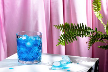 Eski moda bardakta buzlu mavi curacao kokteyli. Aşk merdiveni ile pembe bir arka planda