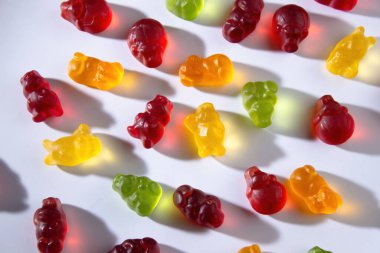 Farklı renklerde marmelat hayvanları ve meyve suyu beyaz arka planda yatar.