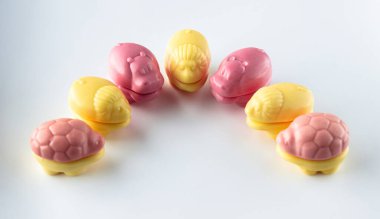 Doğal meyve suları eklenerek reçel çiğnenmesinden yapılan çeşitli yenilebilir hayvanlar. Beyaz arka planda sarı ve pembe çiçekler. Çocuk tatlıları.