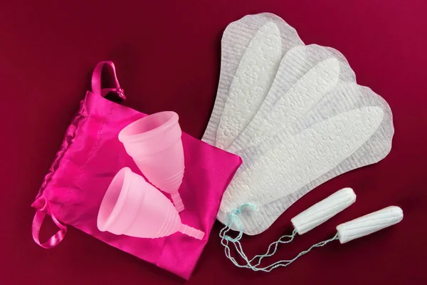 Different types of feminine menstrual hygiene materials products such as pads cloths tampons and cups. dark red background. Menstruation and feminine hygiene concept.