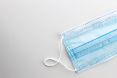 Plastik kulaklıklı cerrahi maske. Ağzı ve burnu kaplayan tipik bir üç katmanlı cerrahi maske. Bakteri maskesi prosedürü. Koruma kavramı.