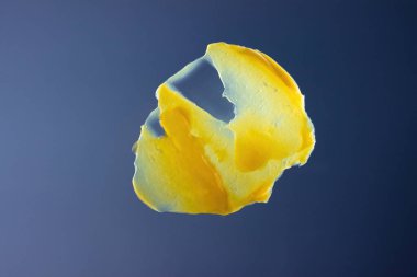 A smear of a yellow cosmetic product on a dark blue background
