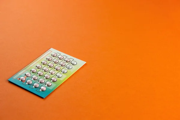 Female oral contraceptive pills blister on orange background. Female contraceptive hormonal birth control pills. The concept of pregnancy planning. copy space