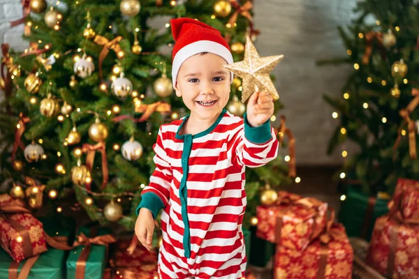 Küçük mutlu bir çocuk elinde Noel ağacından bir yıldız tutuyor, tatil konsepti..