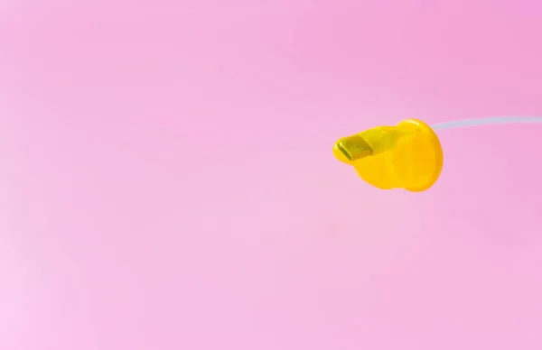 Кабель USB в презервативе является символом компьютерной безопасности. белый кабель в желтом презервативе на розовом фоне — стоковое фото