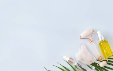 Mavi arka planda paten ve masaj kazıyıcısı gua sha ve kozmetik. Serum, yağ ve cilt bakım ürünleri. Sağlık kavramı..