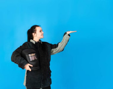 Koruyucu kaynak kıyafeti giymiş ve maskeli mutlu bir esmer kız metni işaret ediyor. Metin için boşluk. Erkeklerin meslekleri.