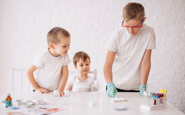 Küçük komik çocuklar laboratuarda deney yapıyorlar. Çocuk deney yapmak için bir çeşit toz döküyor. Bilim ve eğitim.