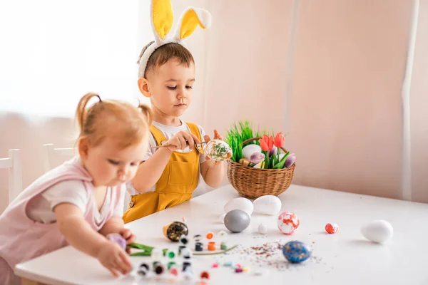 一个小女孩和一个长在兔子耳朵里的欧洲男孩在头上画复活节彩蛋 复活节的概念 准备复活节 复活节快乐 — 图库照片