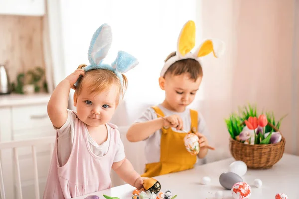 一个小女孩和一个长在兔子耳朵里的欧洲男孩在头上画复活节彩蛋 复活节的概念 准备复活节 复活节快乐 — 图库照片